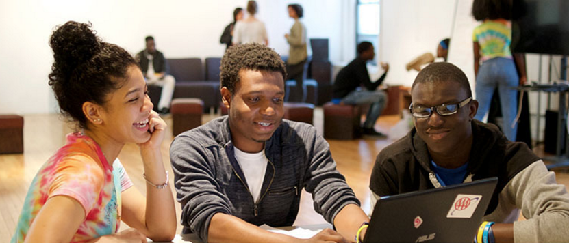 students working on a project in front of a laptop