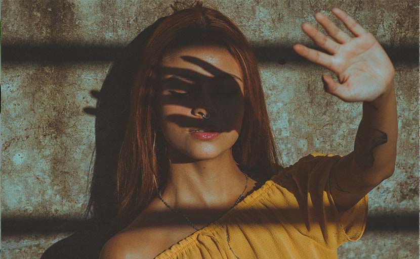 image of woman with hand shielding her face from the sun