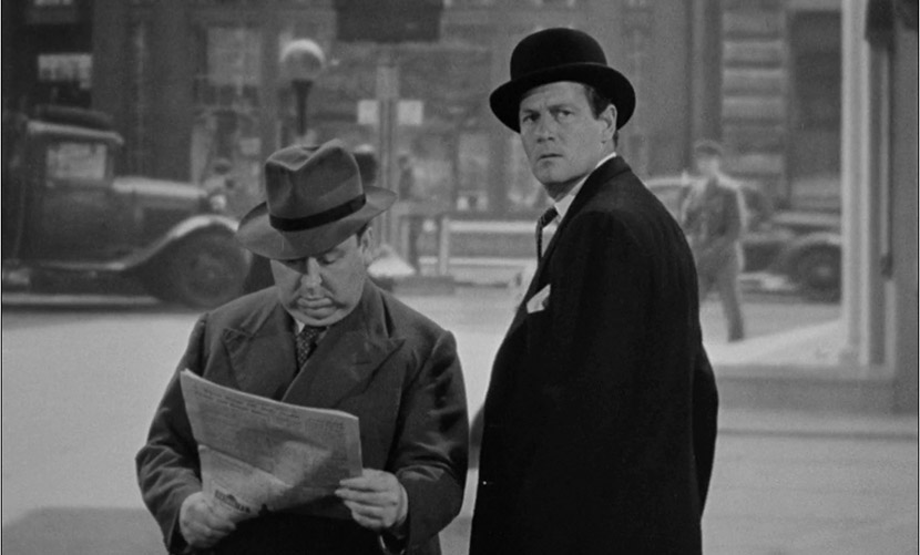 Alfred Hitchcock reading a newspaper in a scene from a film