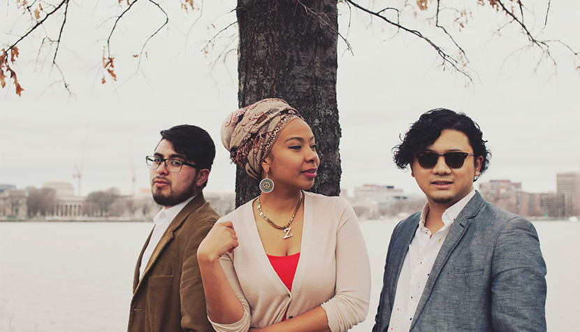 three musicians posing in front of a tree