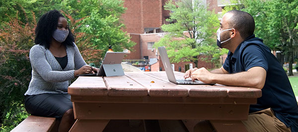 two students with laptops at a table 