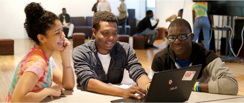 three student interns sitting at a table discussing a project