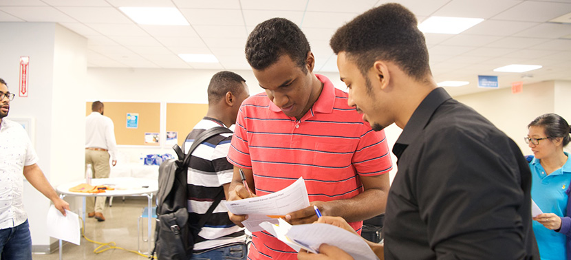 a few black and Latino males students looking over some papers