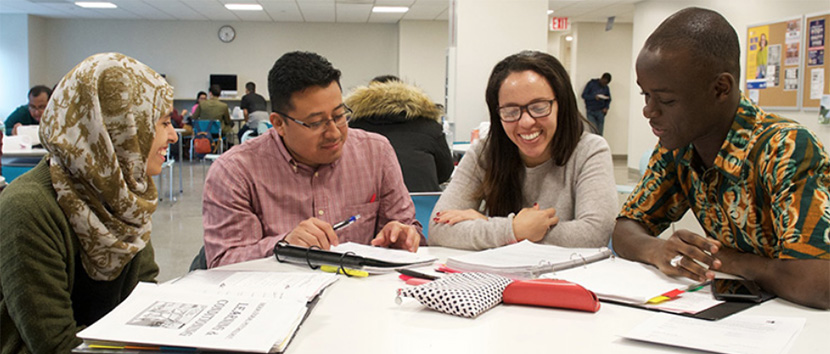 students sitting at round table discussing homework papers on the table