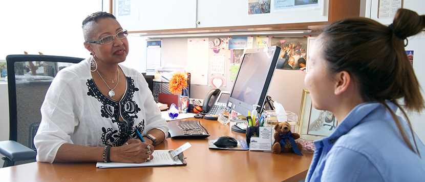 counselor and student sitting at a desk having a discussion