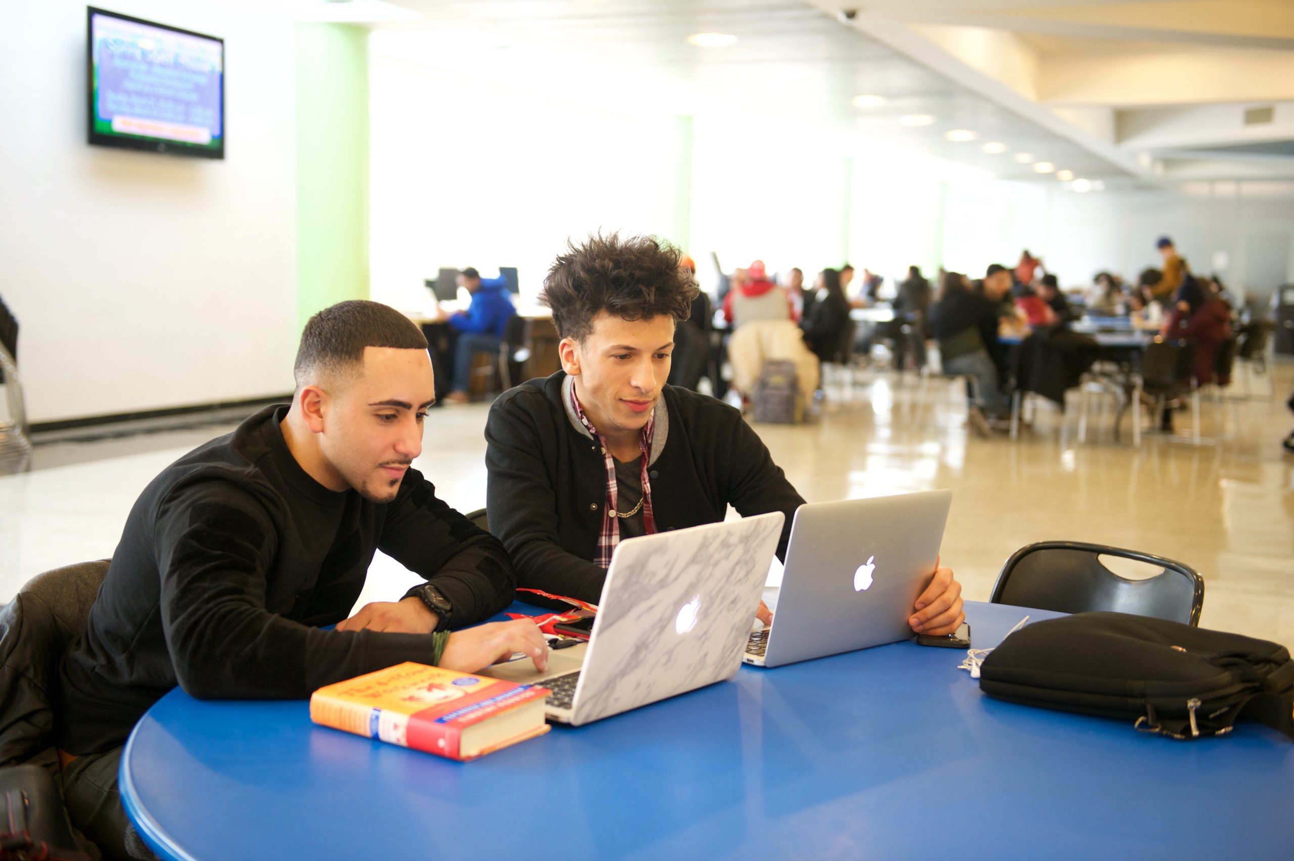 students using laptops at table in cafeteria