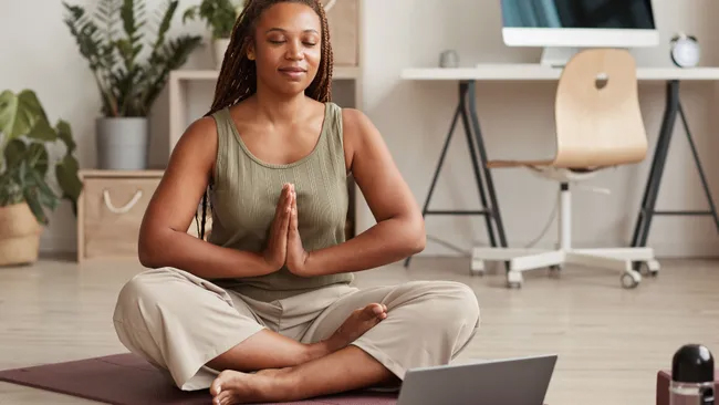 woman meditating in front of laptop computer