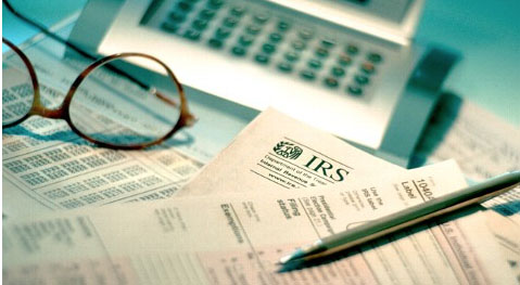 income tax forms with pen on top and computer keyboard nearby